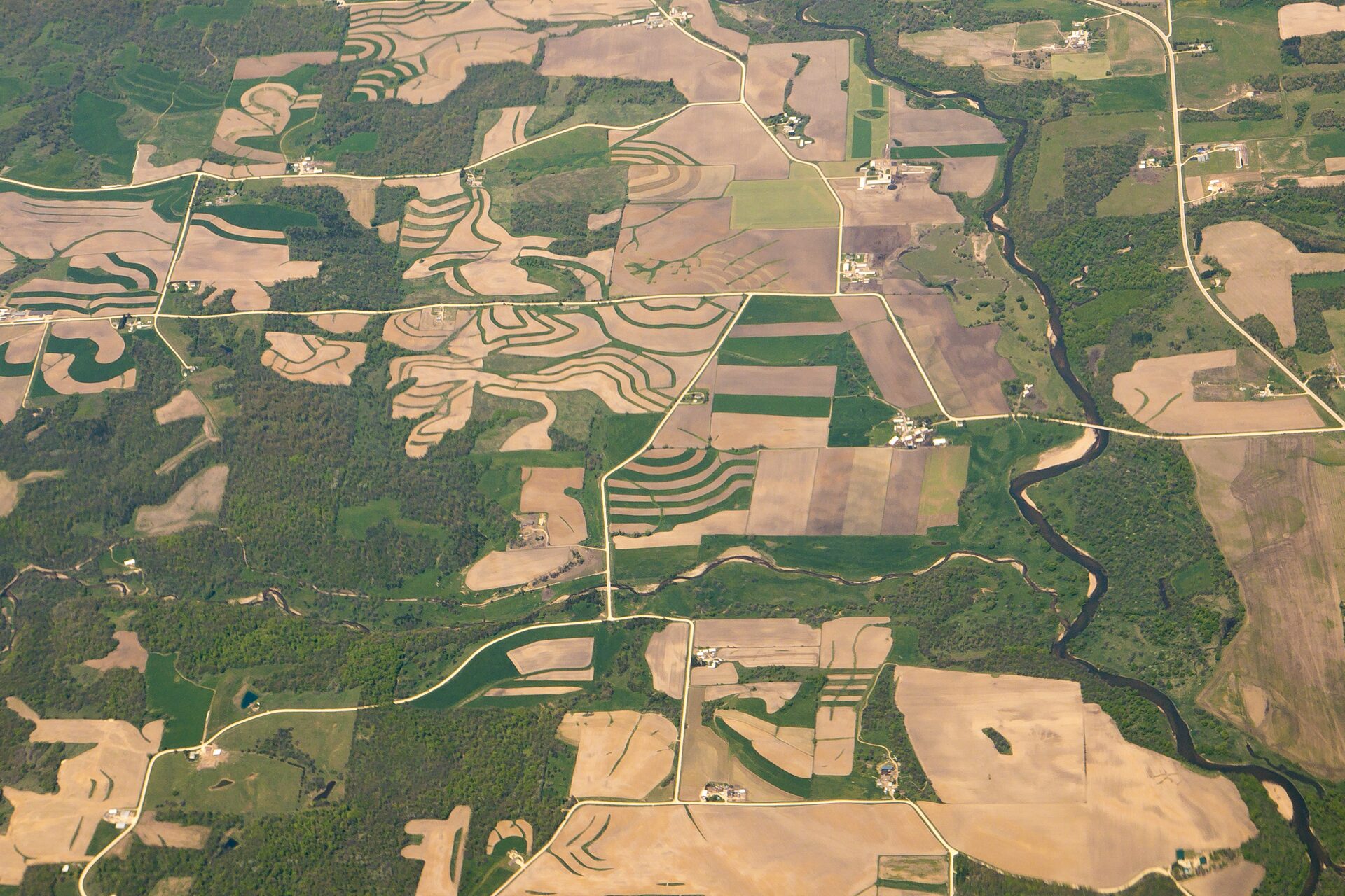 Aerial photograph of terraced fields, wooded ridges, and a winding waterway in northeast Iowa.